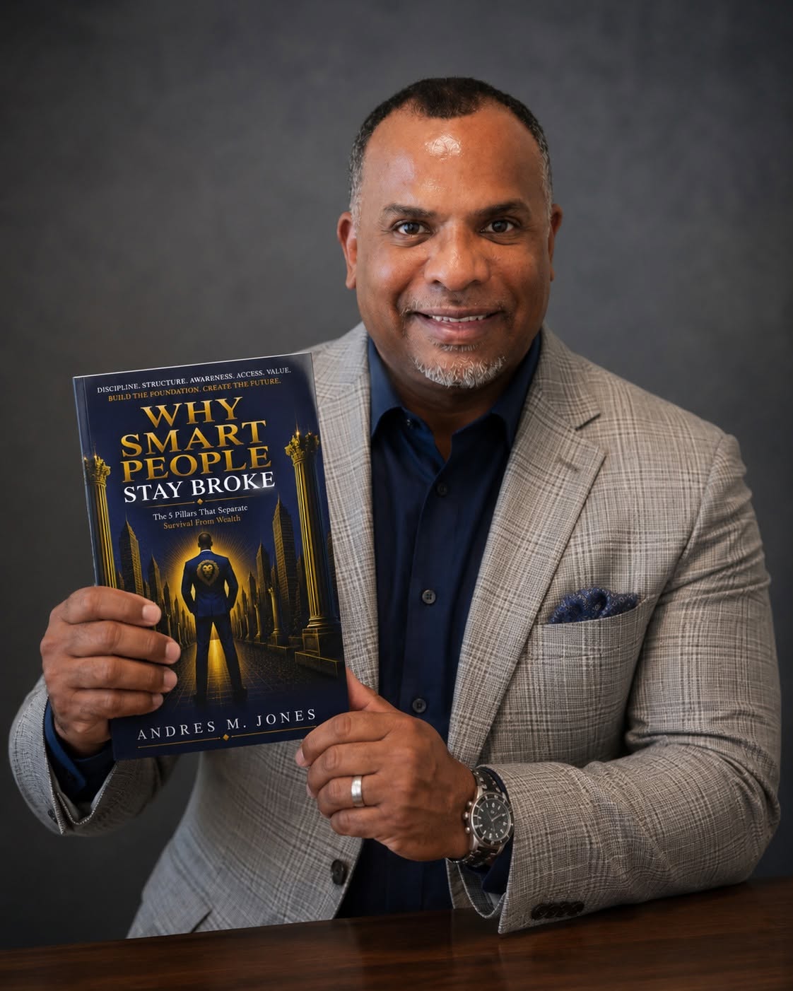Andres M. Jones holding a copy of Why Smart People Stay Broke